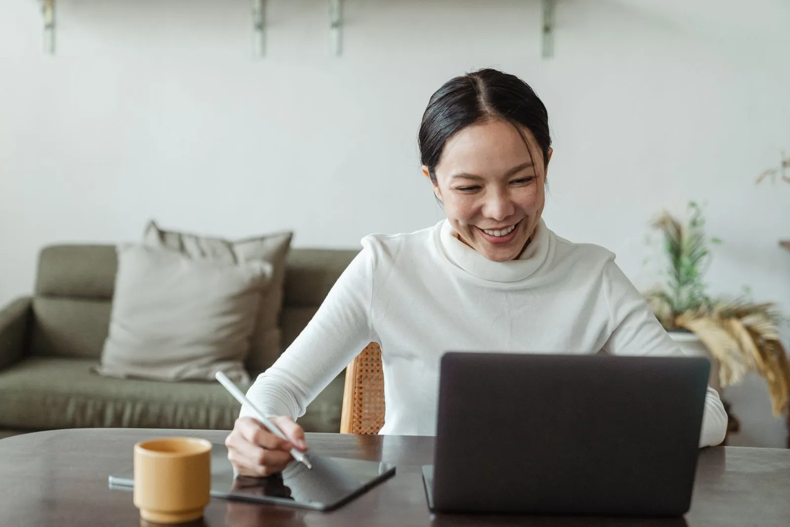 An Asian woman smiling during a video call on her laptop