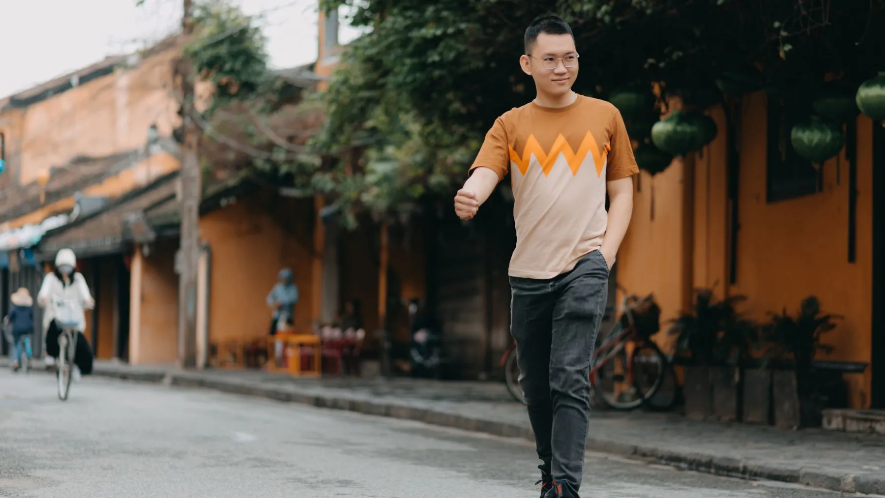 A smiling Asian man walking confidently through a city street in Vietnam.