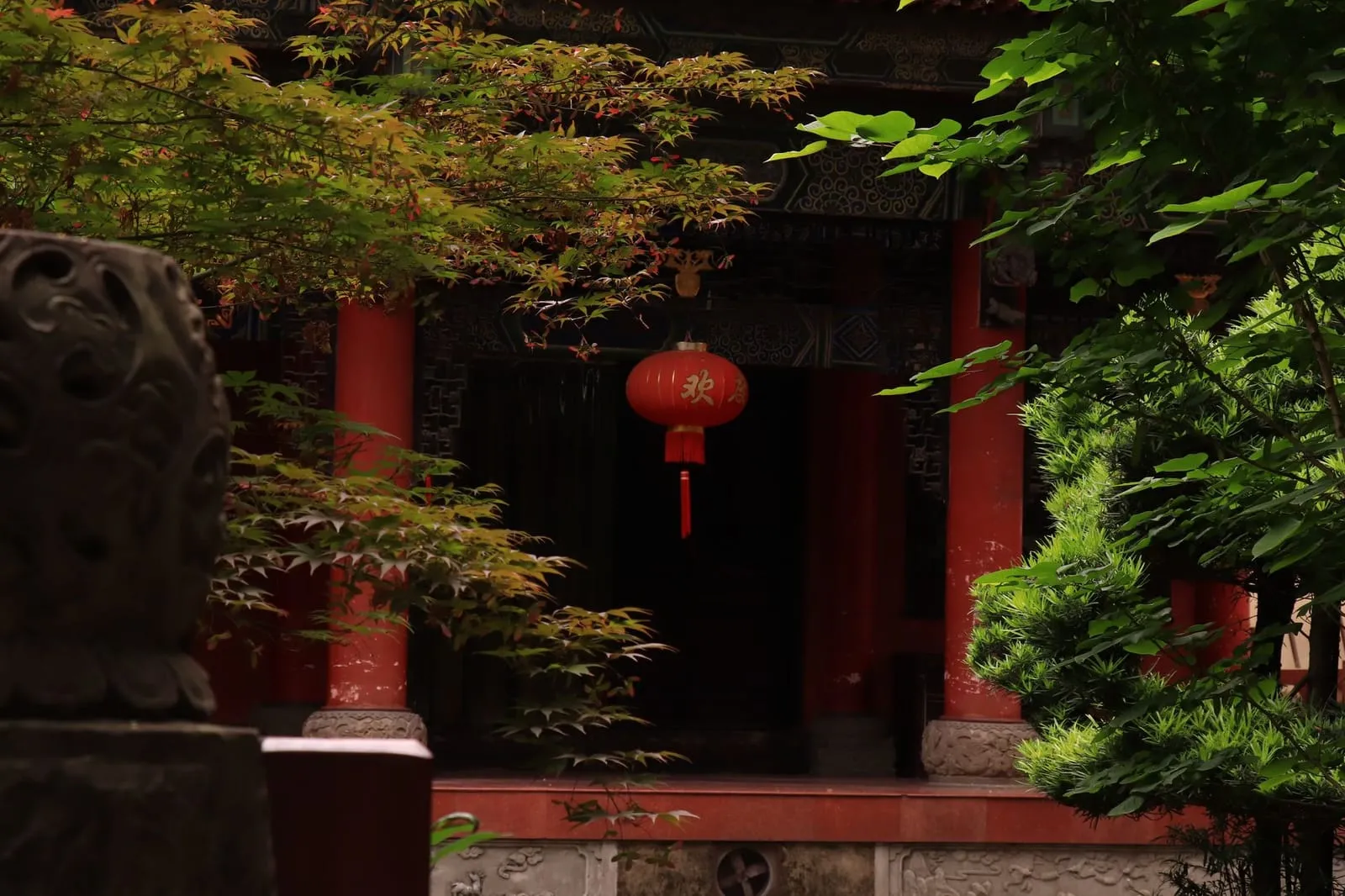 A peaceful temple courtyard framed by lanterns and greenery.